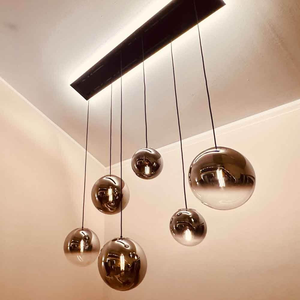 s.luce Orb Esstisch-Hängeleuchte 5-flammig 160cm mit schimmernden Kugeln in einem modernen Raum.