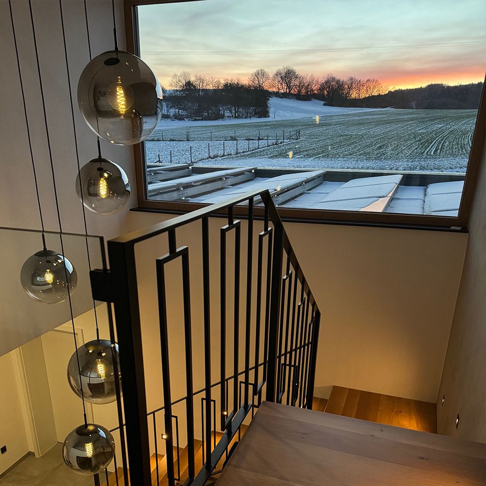 s.luce Orb Galerie lamp 8-vlamig Modular hangt boven de trap met uitzicht op de wintertuin.