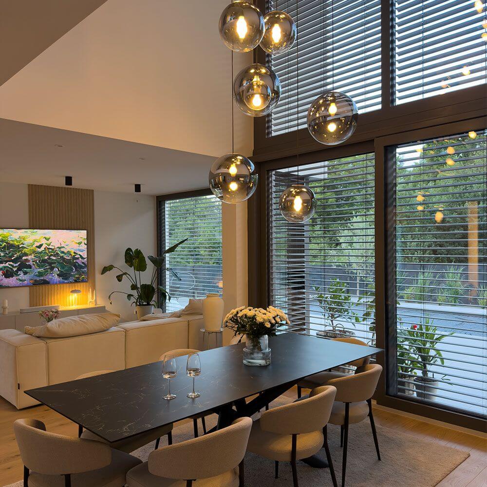 s.luce Orb Galerielampe 8-flammig Modular über einem eleganten Esstisch in modernem Wohnraum.