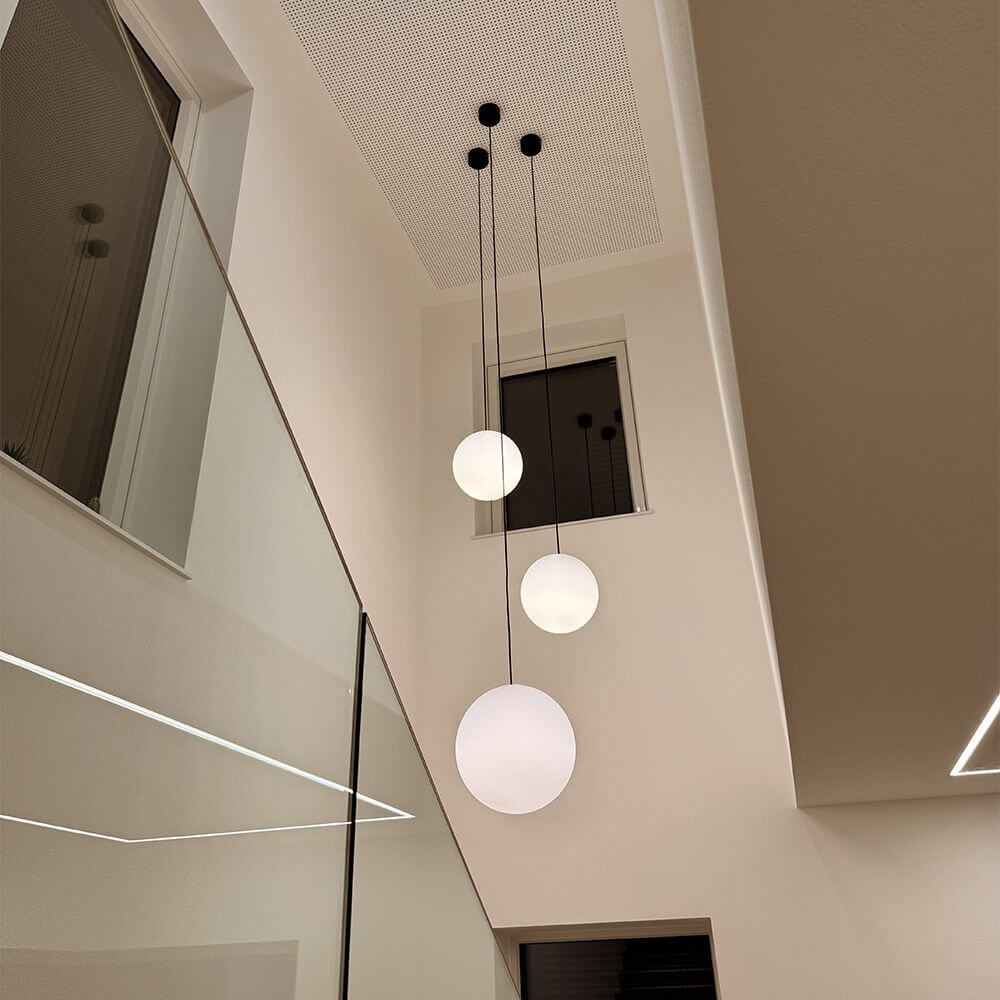 s.luce Orb Glaskugel Galerieleuchte 500cm Aufhängung Schwarz im modernen Interieur mit drei schwebenden Glaskugeln.