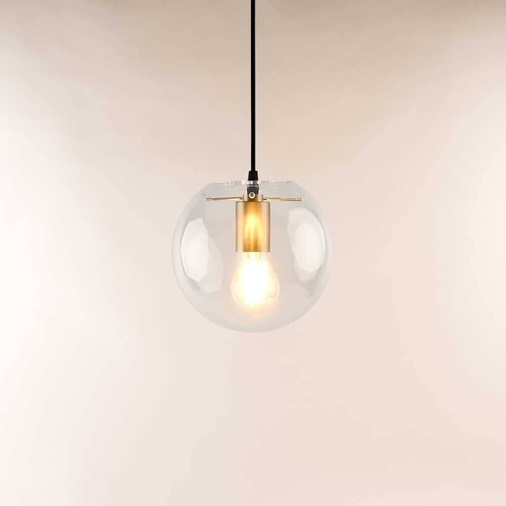 s.luce Orb Glaskugel Hängeleuchte mit klarer Glaskugel und goldener Fassung über heller Wand.