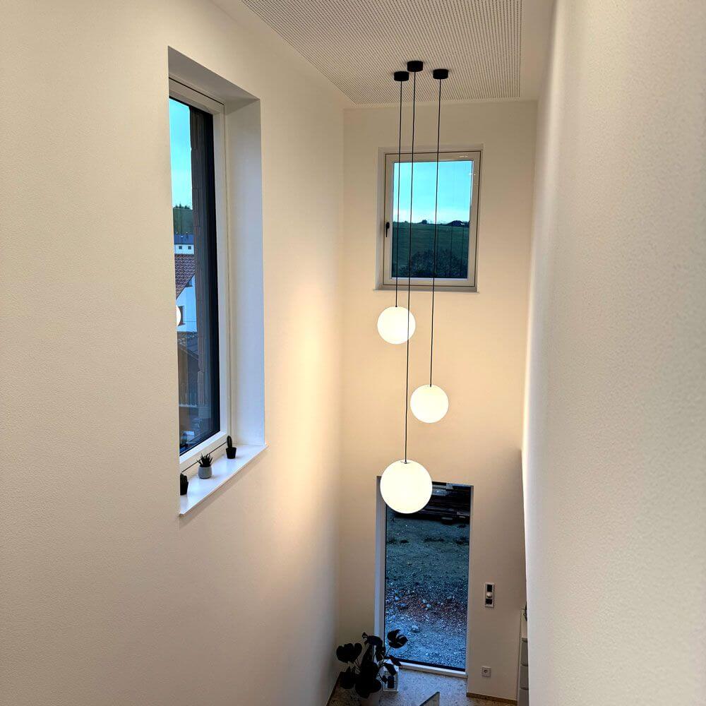 s.luce Orb Glaskugel Hängeleuchte in einem modernen Treppenhaus mit großen Fenstern.