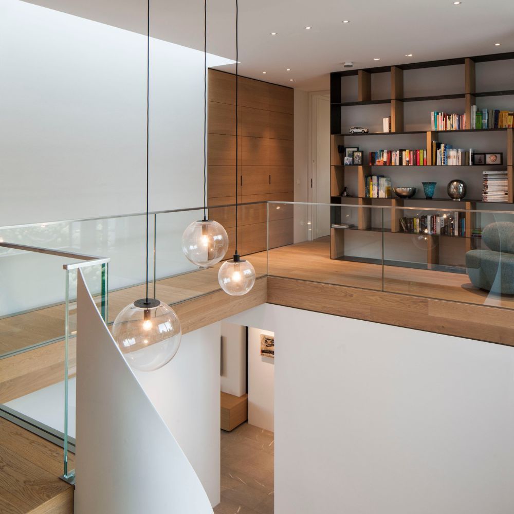 s.luce Orb glass ball pendant light in a modern living space with glass railing and bookshelf.