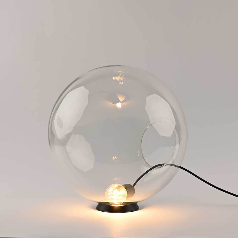 s.luce Orb Glaskugel Tischlampe in minimalistischem Design mit transparentem Globus und schwarzem Metallring.