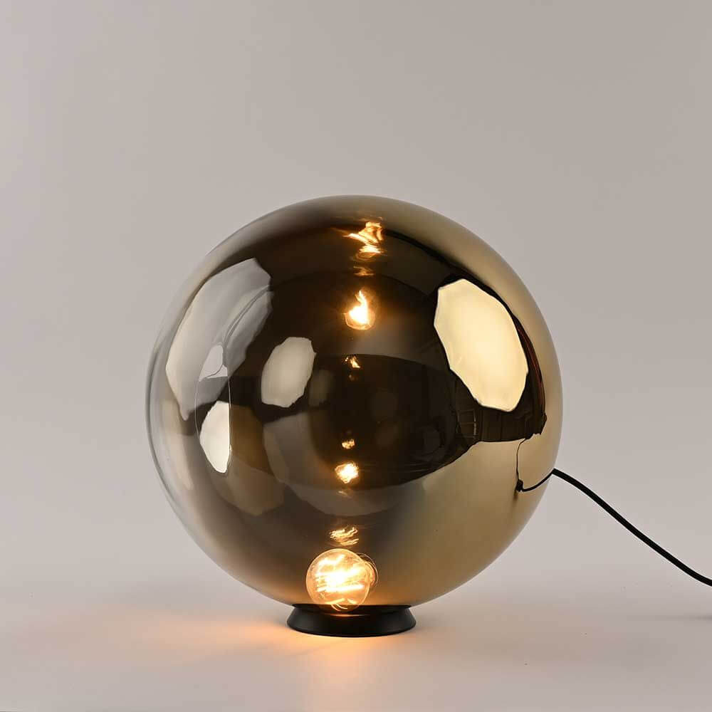 s.luce Orb Glaskugel Tischlampe in gold, minimalistische Eleganz, modernes Design auf schwarzem Metallring.