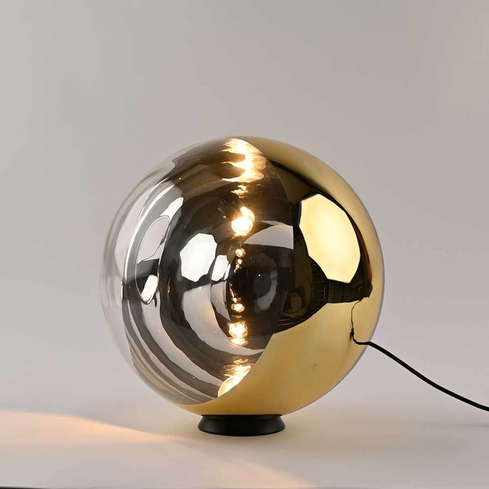 s.luce Orb Glaskugel Tischlampe mit goldener und transparenter Glaskugel, elegant auf schwarzem Metallring.