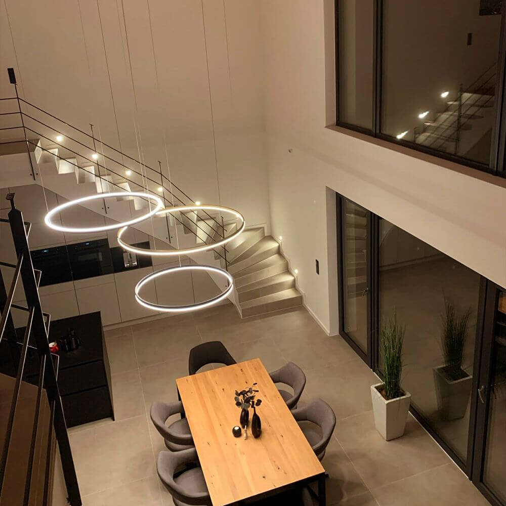 s.luce LED Ring Pendellampe in modernem Wohnraum über Esstisch mit Treppe und großem Fenster