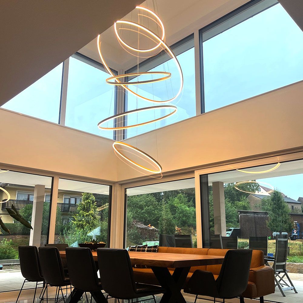 s.luce Lampada a sospensione LED a forma di anello Ø 120 cm in una zona pranzo moderna con grandi finestre e design elegante.