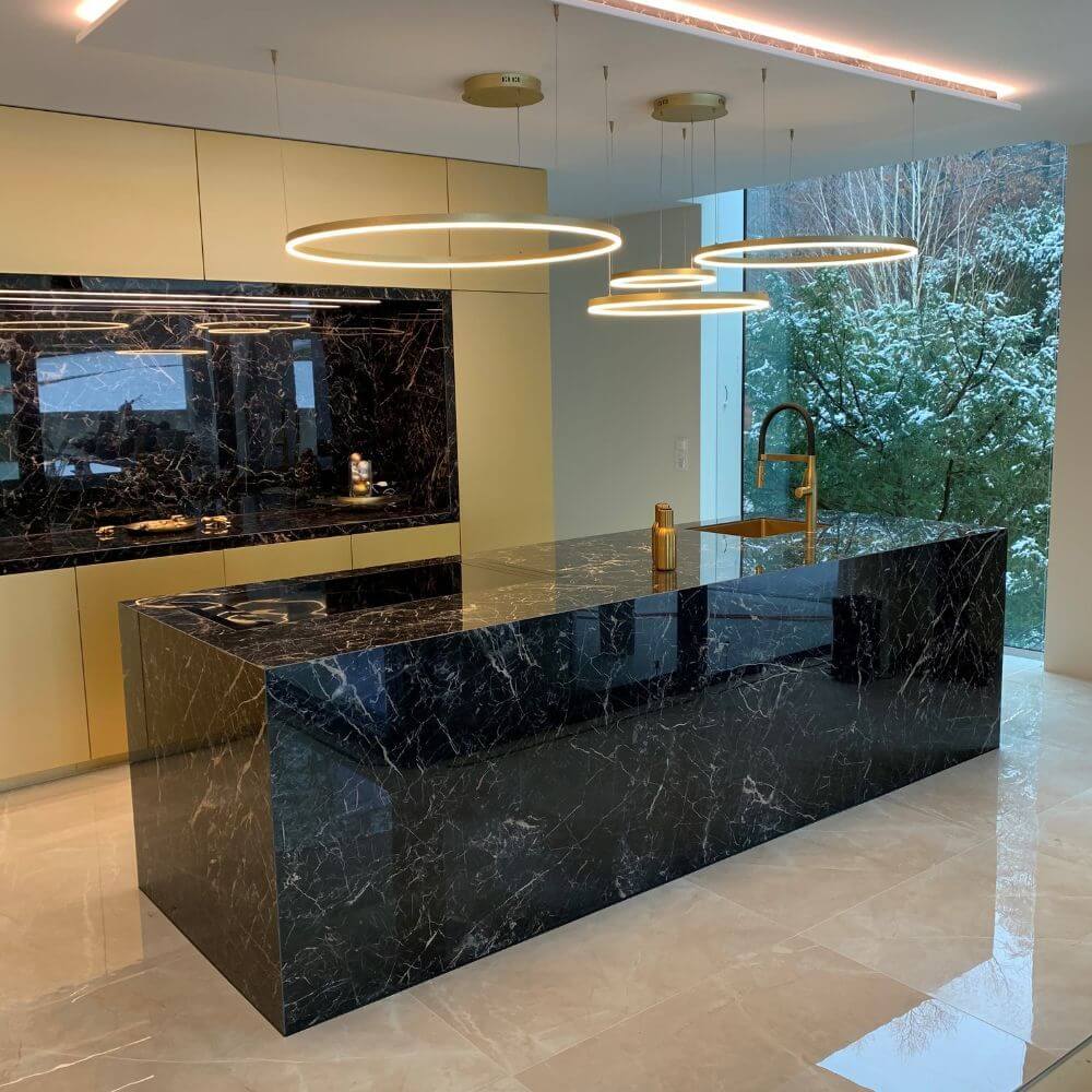 s.luce LED Ring Pendelleuchte Ø 40cm über einer eleganten Kücheninsel aus schwarzem Marmor.