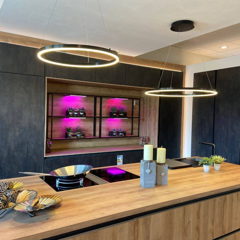 s.luce LED Suspension anneau Ø 60 cm au-dessus d’un îlot de cuisine moderne avec un plateau en bois.
