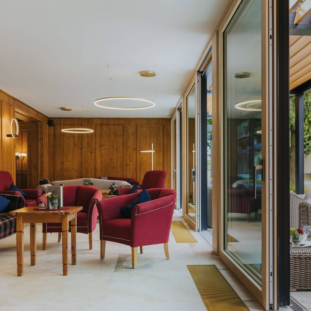 Moderne s.luce LED Ring Hängeleuchte in einem stilvollen Wohnzimmer mit gemütlichen roten Sesseln.