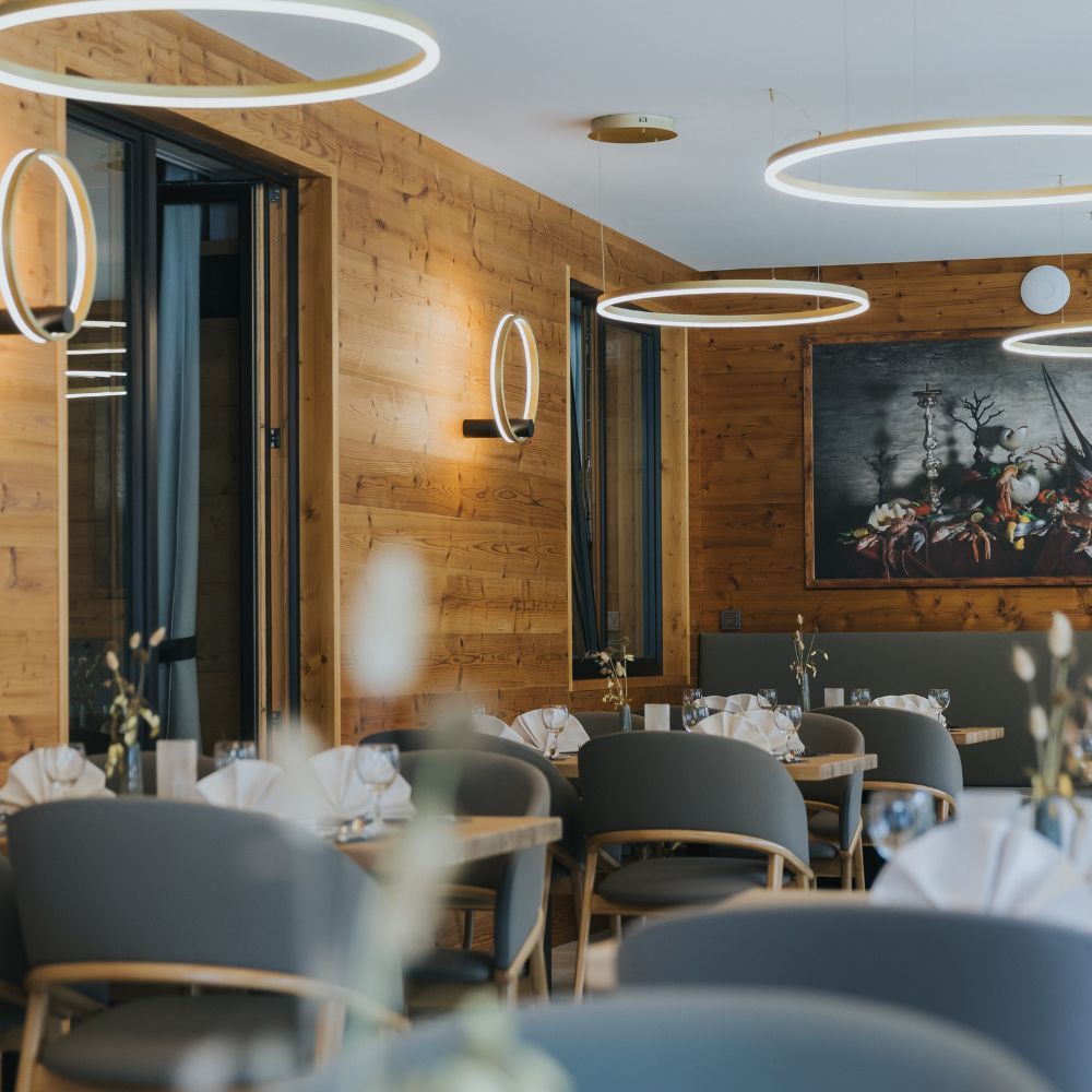 Moderne s.luce Ring Air LED Wandleuchten in einem Holzrestaurant mit eleganten Tischen und Stühlen.