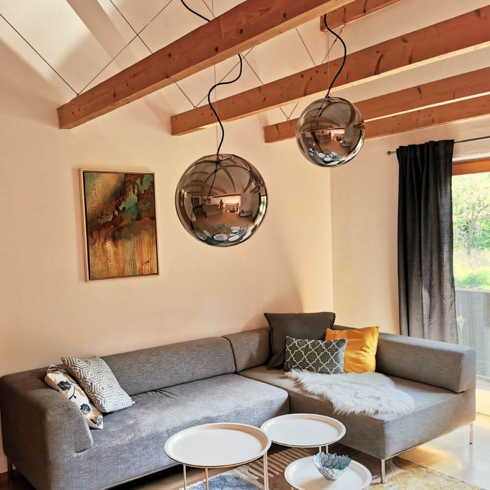 s.luce Sphere Pendelleuchte Glaskugel im modernen Wohnzimmer über grauem Sofa.