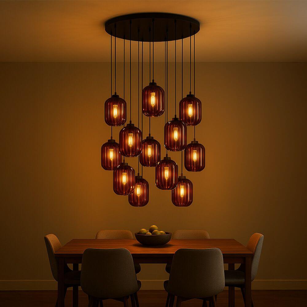 s.luce Velo Galerie-Hängeleuchte 12-flammig Ø 80cm Ø 25cm mit warmem Licht über einem Esstisch.