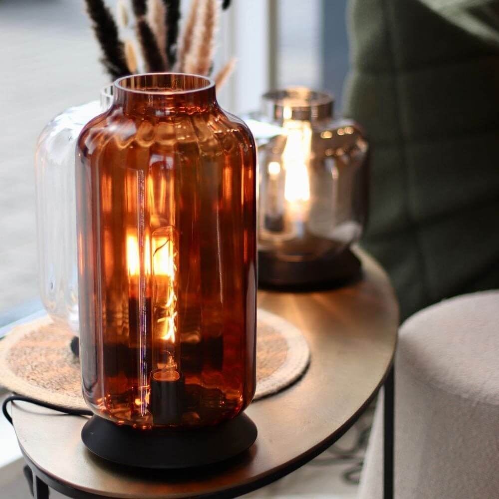 s.luce Velo Glas-Tischleuchte mit Schalter in rauch und cognac auf einem Tisch.