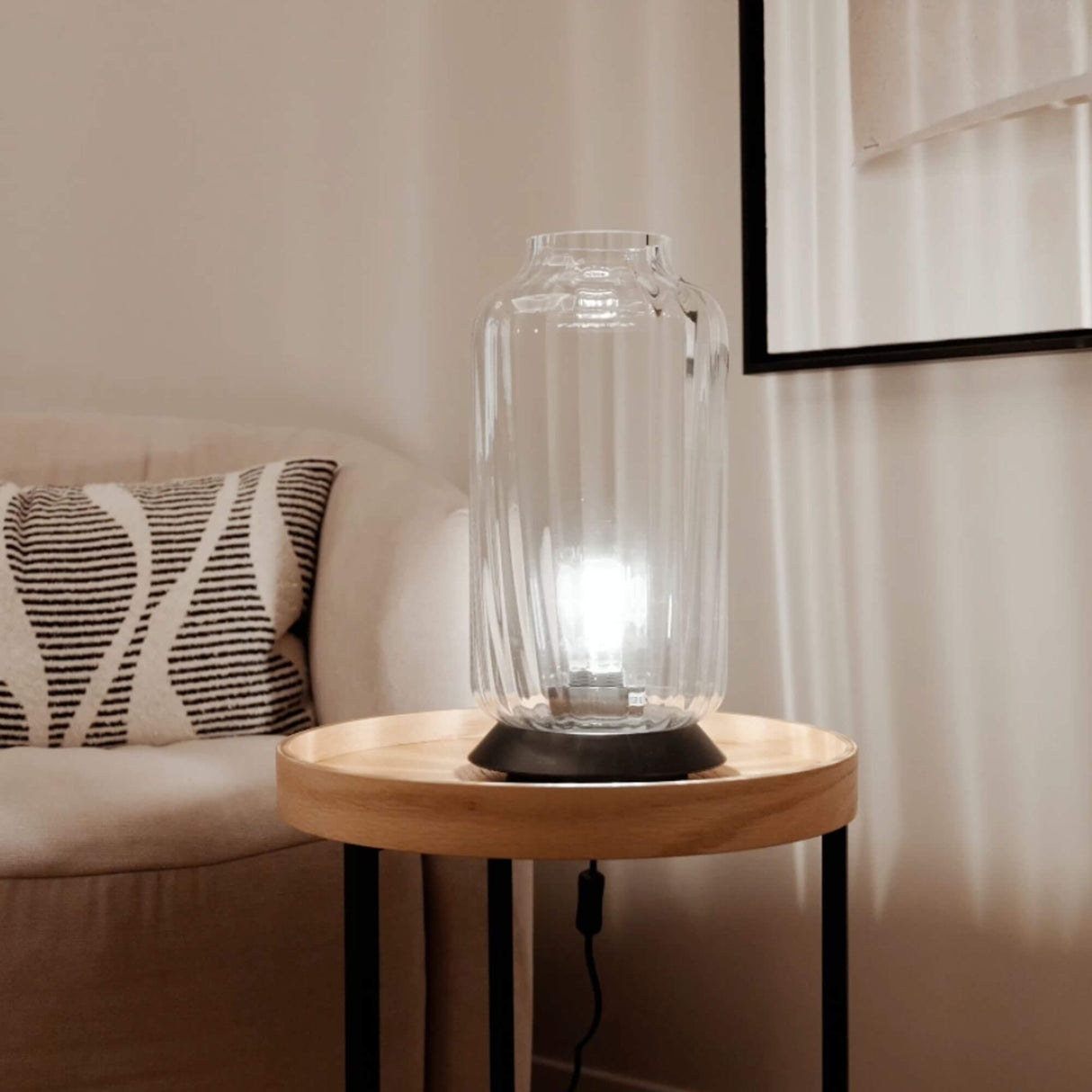 s.luce Velo Glas-Tischleuchte mit Schalter auf einen Holzbeistelltisch in einem modernen Raum.