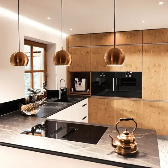 Moderne Küche mit Holzmöbeln, eleganten Kupferlampen und einer eleganten Arbeitsfläche aus Stein.