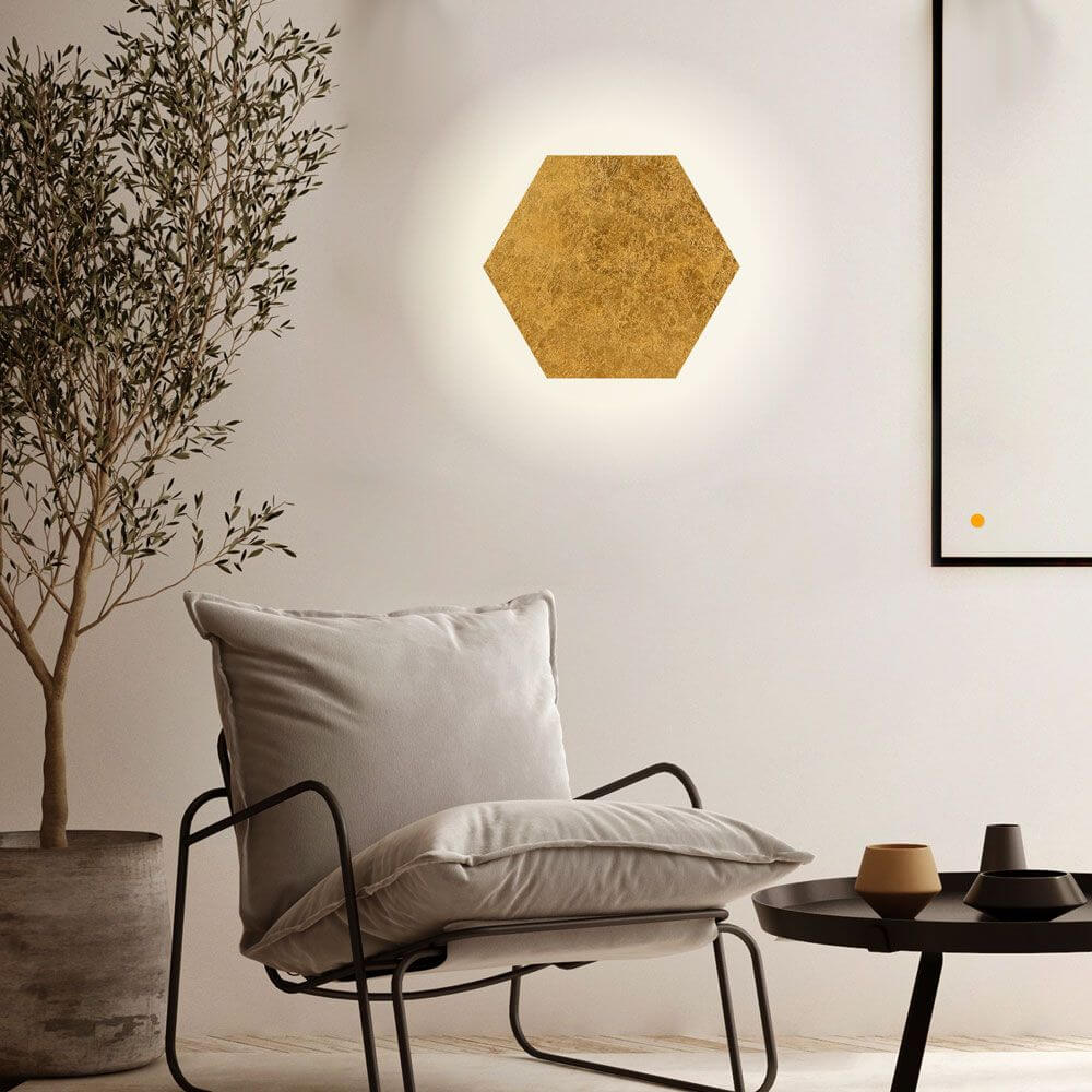 s.luce Hive indirekte LED Wandleuchte in Form eines goldenen Hexagons an einer Wand, moderner Raum mit Möbeln.