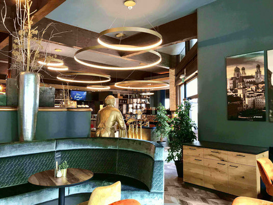 Modernes Café mit stilvoller Einrichtung, goldener Statue und eleganten Lichtringen im Hintergrund.