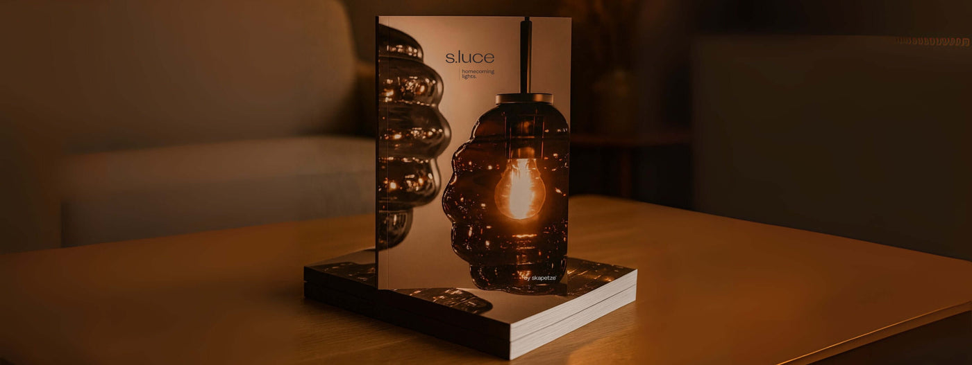 Abendliche Beleuchtung mit S.luce Lampen präsentiert in einem stilvollen Katalog auf einem Tisch.