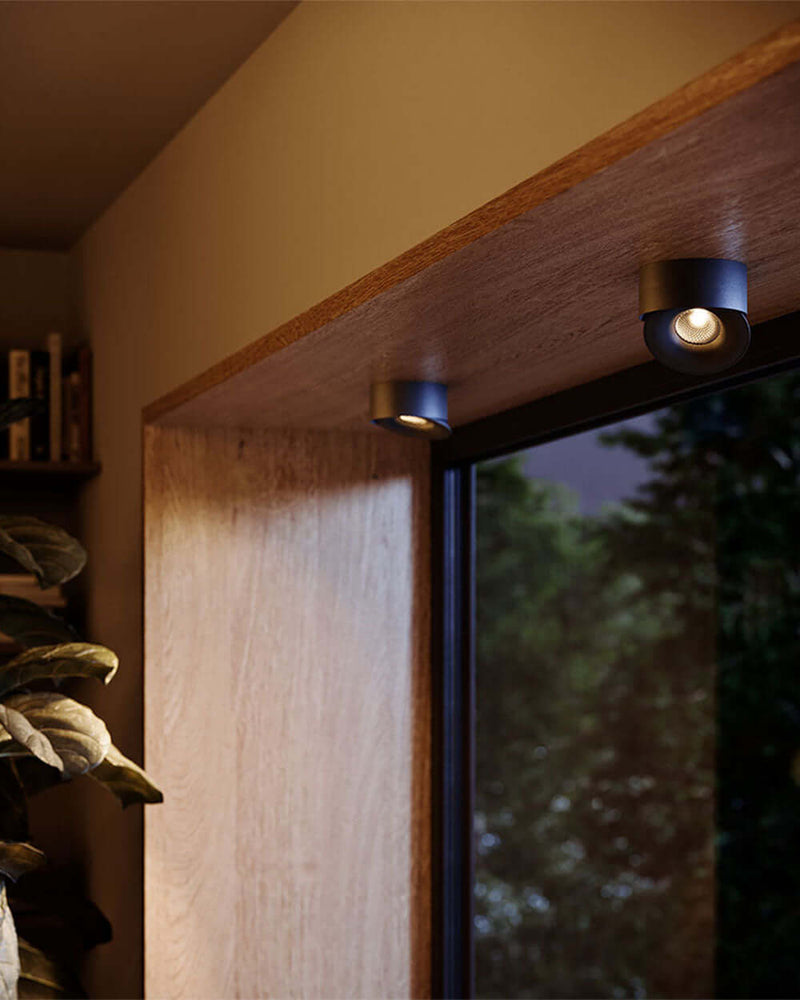 Dezente Wandbeleuchtung über einem Fenster in einem modernen Raum mit Holzverkleidung.