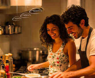 Junges Paar kocht zusammen in moderner Küche und genießt die Vorbereitung von frischen Zutaten.