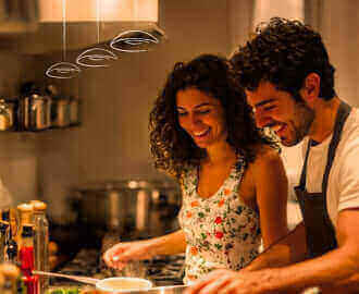 Junges Paar kocht zusammen in moderner Küche und genießt die Vorbereitung von frischen Zutaten.