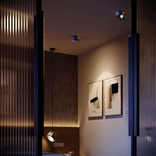 Gemütliches Schlafzimmer mit moderner Beleuchtung und Kunstwerken an der Wand.