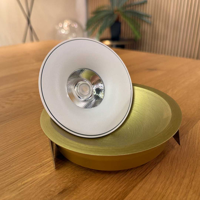 Moderne Leuchte auf goldenem Tisch, elegantes Design mit weißem Reflektor und stilvoller Schale.
