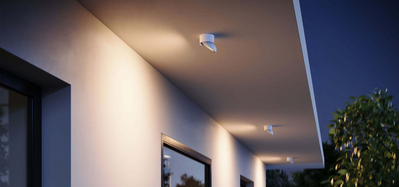 Moderne Außenbeleuchtung unter einem Vordach bei Nacht, hell erleuchtet von Deckenleuchten.