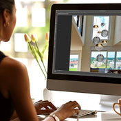 Frau arbeitet an einem Computer mit Fotomontage einer modernen Pendelleuchte im Wohnraum.