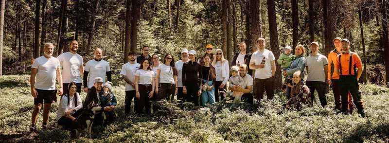 Gruppenshooting im Wald mit Teilnehmern in weißen T-Shirts, umgeben von Bäumen und Pflanzen. Natur und Gemeinschaftsgefühl.