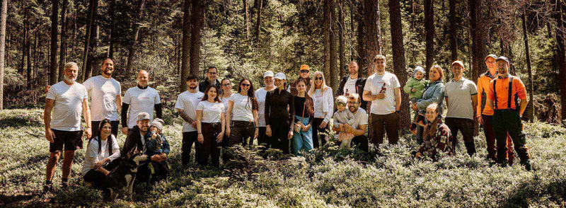 Gruppenshooting im Wald mit Teilnehmern in weißen T-Shirts, umgeben von Bäumen und Pflanzen. Natur und Gemeinschaftsgefühl.