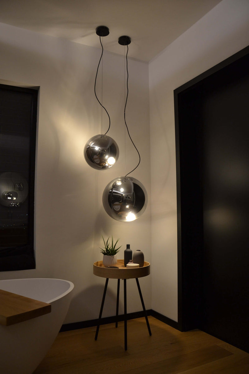 Moderne s.luce Pendelleuchten in einem stilvollen Badezimmer mit Holzdetails und Pflanzen.