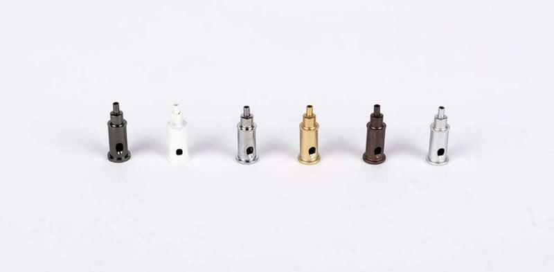 Sechs verschiedene Ventile in Schwarz, Weiß, Gold und Silber auf hellem Hintergrund.