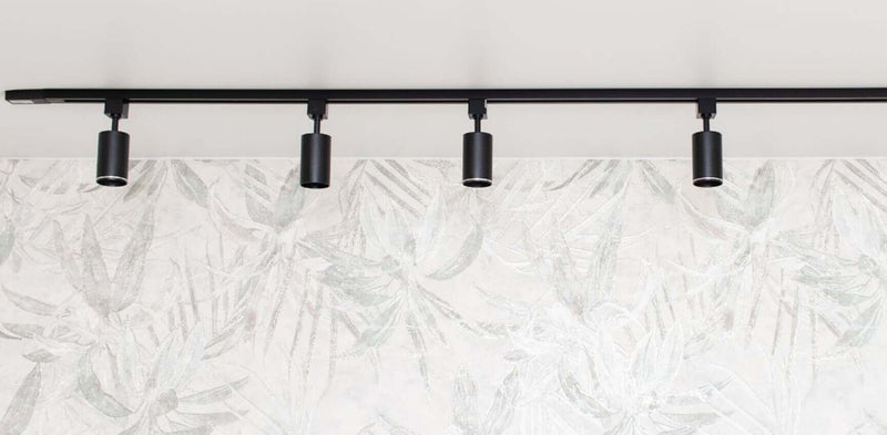 Schwarze Deckenleuchten an einem leichten, pflanzenmotivierten Hintergrund.