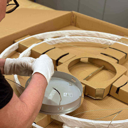 Person in gloves montiert eine Leuchte aus Kartonverpackung, sorgfältige Handhabung der Teile.