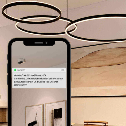 Smartphone zeigt Nachricht über Design und Community in modernem Raum mit hängenden Leuchten.
