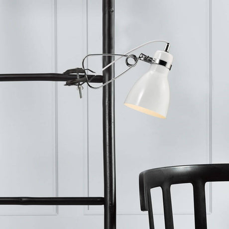 Cyclone Clamp Light White on a shelf above a black chair, modern and timeless design.