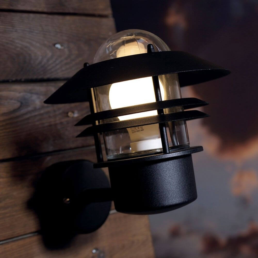 Schlichte schwarze Blokhus Außen-Wandleuchte IP54 an Holzwand, perfekt für verschiedene Außenbereiche.