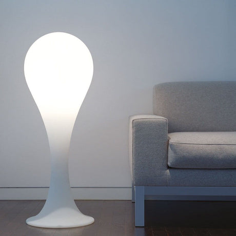 Lampada da terra Drop-4L 100 cm Liquid-Light bianca accanto a un divano moderno in uno spazio minimalista.