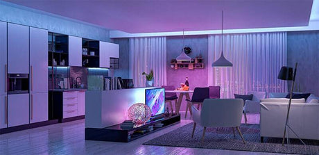 Modernes Wohnzimmer mit smarten Lampen in lila und blauen Lichttönen für individuelle Akzentbeleuchtung.