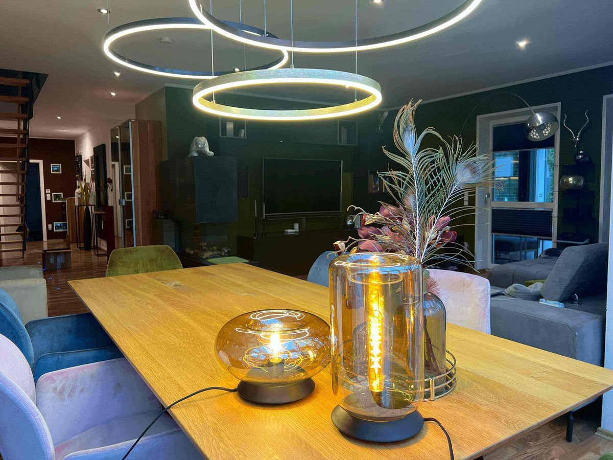 Esstische als Herzstück des Hauses mit stilvollen Lampen und eleganter Dekoration auf einem Holzstuhl.