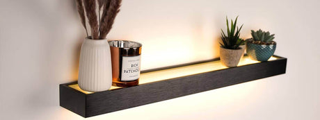 Wandboard mit LED-Beleuchtung, dekoriert mit Pflanzen und einer Kerze in einem modernen Innenraum.