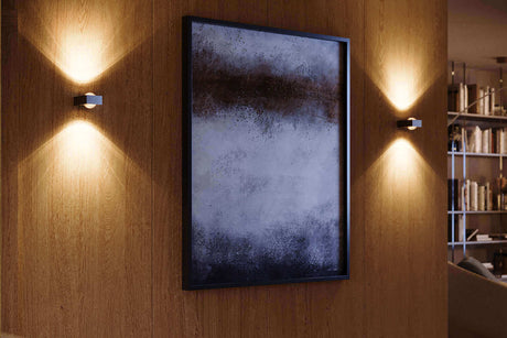 Moderne Wandleuchten beleuchten ein abstraktes Gemälde an einer Holzwand in einem stilvollen Wohnraum.