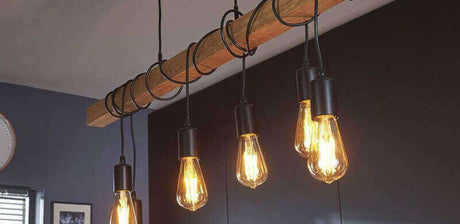 Hängende Holzlampe mit mehreren Glühbirnen, erzeugt warmes Licht in modernem Wohnraum.