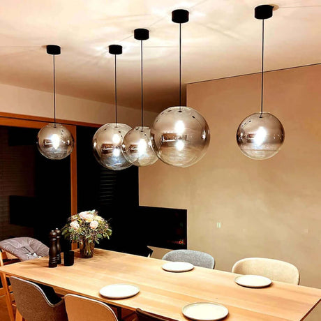 Moderne Lampe mit Glaskugeln über einem Esstisch, ideal für stilvolle Innenräume und als Trendsetter in der Beleuchtung.