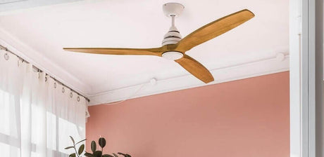 Deckenventilator mit Holzblättern in einem modernen Raum mit rosa Wandfarbe.