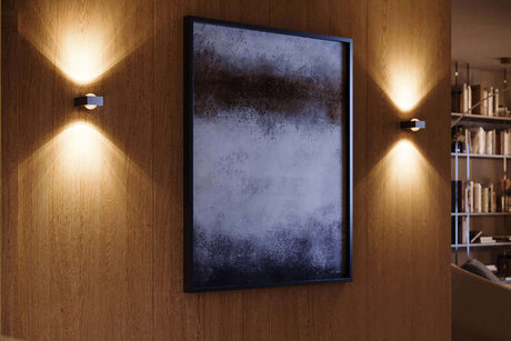 Moderne Wandleuchten an einer Holzwand, die ein Kunstwerk stimmungsvoll beleuchten.
