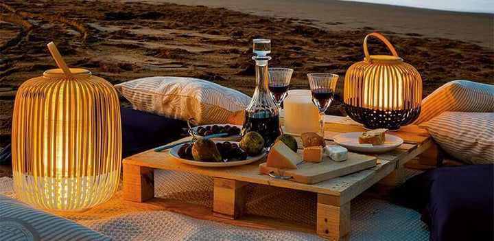Die Vorteile von Indoor und Outdoor Tischlampen: stilvolle Tischlampen bei einem romantischen Picknick am Strand.